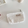 Detail van de witte 3D-bloemenreliëf en geweven label op een stoffen cosmetische tas - Jacquard Roos Wit