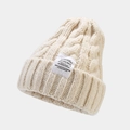 Detailed close-up of cream knit beanie featuring thick cable patterns and fashion label - Off White