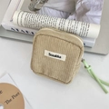 Detailed texture of khaki corduroy makeup bag with a green zipper pull on vintage books - Apricot