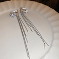 Detailed shot of silver tassel star earrings with sparkling zircon inlay on white ceramic - Silver Star Tassel Ear Clip