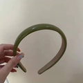 Minimalist green leather headband with soft inner lining shown in a hand-held view - Fruit Green
