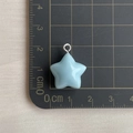 Detalle de colgante de estrella azul de resina de 1,5 cm con aro metálico sobre tapete - Colgante de estrella azul