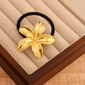 Golden flower metal hair tie with black elastic band on vintage display tray - Gold Lily