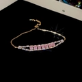 Detailopname van een geometrische armband met roze zirkoon op een zwarte reflectiegrond - 22# Armband - Goud-Roze