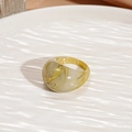 Macro view of amber resin ring with marble texture on a white wavy background - Green Oval