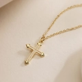 Gros plan d'un collier pendentif croix plaqué or 18K avec zircon sur fond texturé - Collier Croix en Zircon Doré (24795)