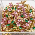 Detailansicht der Kirsch-Anhänger mit rosa Strasssteinen und Goldmetall in einer Box - Rosa