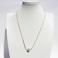 Elegante gouden ketting met een ronde parelhanger getoond op een wit halsmodel voor dames - Premium kristallen parels