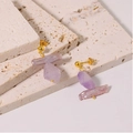Elegante Goldohrringe mit natürlichen lila Edelsteinen auf beiger Steinoberfläche - Barocke Amethyst Asymmetrische Ohrringe