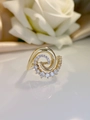 Macro di un anello a spirale dorato con zirconi incastonati su seta bianca - Oro KC