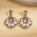 Detalle de pendientes vintage con perlas y cristales sobre fondo de cuero texturizado - Dorado