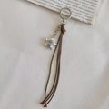 Porte-clés étoile argentée avec pompons en corde marron style rétro Y2K sur fond crème - café