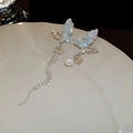 Dettaglio di orecchini a farfalla asimmetrici con cristalli e pendente di perle - No.2 Orecchini a Bottone Asimmetrici con Nappa Farfalla Perla e Cristallo Perno Argento