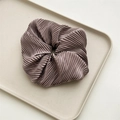 Close-up of a large pleated satin scrunchie with a silky glossy texture in soft mauve color - Creamy Purple