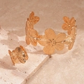 Dettaglio del bracciale rigido a fiori dorati e anello su base in pietra naturale - Oro