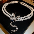 Macro view of double-layer pearl necklace with a sparkling rhinestone butterfly pendant - Rhinestone Butterfly Tassel Pearl Necklace