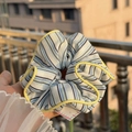 Striped scrunchie with blue and white patterns and yellow contrast edges held by hand - Yellow Trim Blue-White-Black Stripe Scrunchie