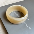 Detail of a wide cream acrylic resin bangle with marble texture on a book - 69# Bracelet-Creamy Cloud Thick