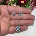 Detailed macro of the round halo zircon pendant and matching stud earrings on palm - White