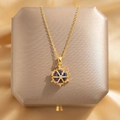 Gold starburst necklace with blue gemstone pendant on a premium jewelry box background - Rudder