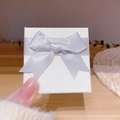 Elegante confezione regalo per gioielli bianca con fiocco in raso lavanda tenuta in mano - Portagioie / Bianco avorio