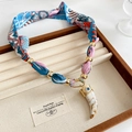 Dettaglio del ciondolo a corno con motivo a occhio e catena a sciarpa di seta colorata - Collana-Oro-Blu-Rosa-Ciondolo Avorio