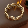 Macro shot of gold floral metal links with vintage texture on a brown leather base - Gold