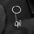 Polished silver stainless steel alphabet W keychain with circular ring on stone background - Letter W