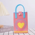 Detailed texture of pink knitted handbag featuring yellow heart patch and blue handle - Pink