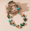 Detalle de collar bohemio de capas con cuentas turquesas y bronce sobre piedra natural - Azul
