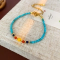 Détail d'un bracelet en perles colorées avec fermoir doré sur support en lin - Style Bleu Turquoise en Pierre Artificielle