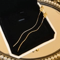 Close-up of golden knot tassel earrings with metallic finish in a luxury jewelry box - Knot Tassel Dangle / Gold