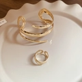Gedetailleerd zicht van de gouden spiraal armband en ring op keramische schaal - Armband Ring Set - Goud