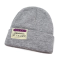 Detailed view of grey knitted beanie featuring a vintage yellow boarding pass patch - Gray