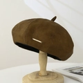 Deep brown faux leather beret with gold metal accent shown on a wooden stand - Suede / Camel