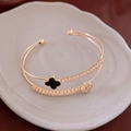 Detalle de brazalete dorado de doble capa con trébol negro y detalles de circón - Negro