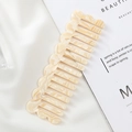 Macro view of beige marble acetate comb with unique wavy teeth on white silk - Yellow