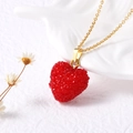 Gros plan du pendentif cœur rouge sur chaîne dorée avec décor en céramique blanche - Rouge