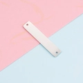 Primer plano de una etiqueta rectangular de acero inoxidable plateado con dos agujeros simétricos - Doble Agujero / 6x32mm / Color Acero