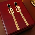 Macro shot of long gold tassel earrings with black square studs on a wooden box - Gold (Real Gold Plated Silver Pin)