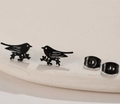Close-up of matte black stainless steel bird studs with butterfly backings on stone - Bird / Black