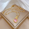 Dettaglio di collana dorata con ciondolo gemma rosa e piume di diamanti su seta - Catena d'oro con ciondolo in pietra rosa