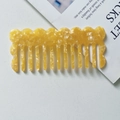 Macro shot of yellow marble acetate wide-tooth comb with wavy edge design on a white background - Yellow