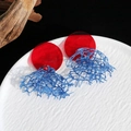Dettaglio degli orecchini in acrilico rosso e blu con pizzo vintage su un piatto decorativo - Orecchini in pizzo acrilico a contrasto rosso blu (2# ago d'argento)