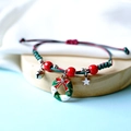 Macro shot of handmade Christmas woven bracelet with bell and enamel wreath charm - Rhinestone Gift Box