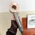 High-speed bladeless hair dryer in rose gold and dark grey finish held by hand - Copper Gold