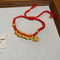 Detail of red braided rope bracelet with golden horse charm and five coins on a tray - 8# Bracelet-Gold-Red-Coins (Zodiac Horse)