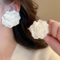 Close-up of elegant white fabric flower earrings with pearls on a model's ear - White