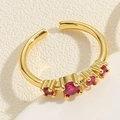 Macro view of gold-plated wave ring featuring five graduated red zircons on a beige background - Geometric / Rose Red Zirconia