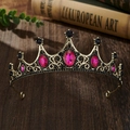 Close-up of vintage golden crown with magenta and black rhinestones on a wooden desk - Bronze Base Rose Red Zirconia